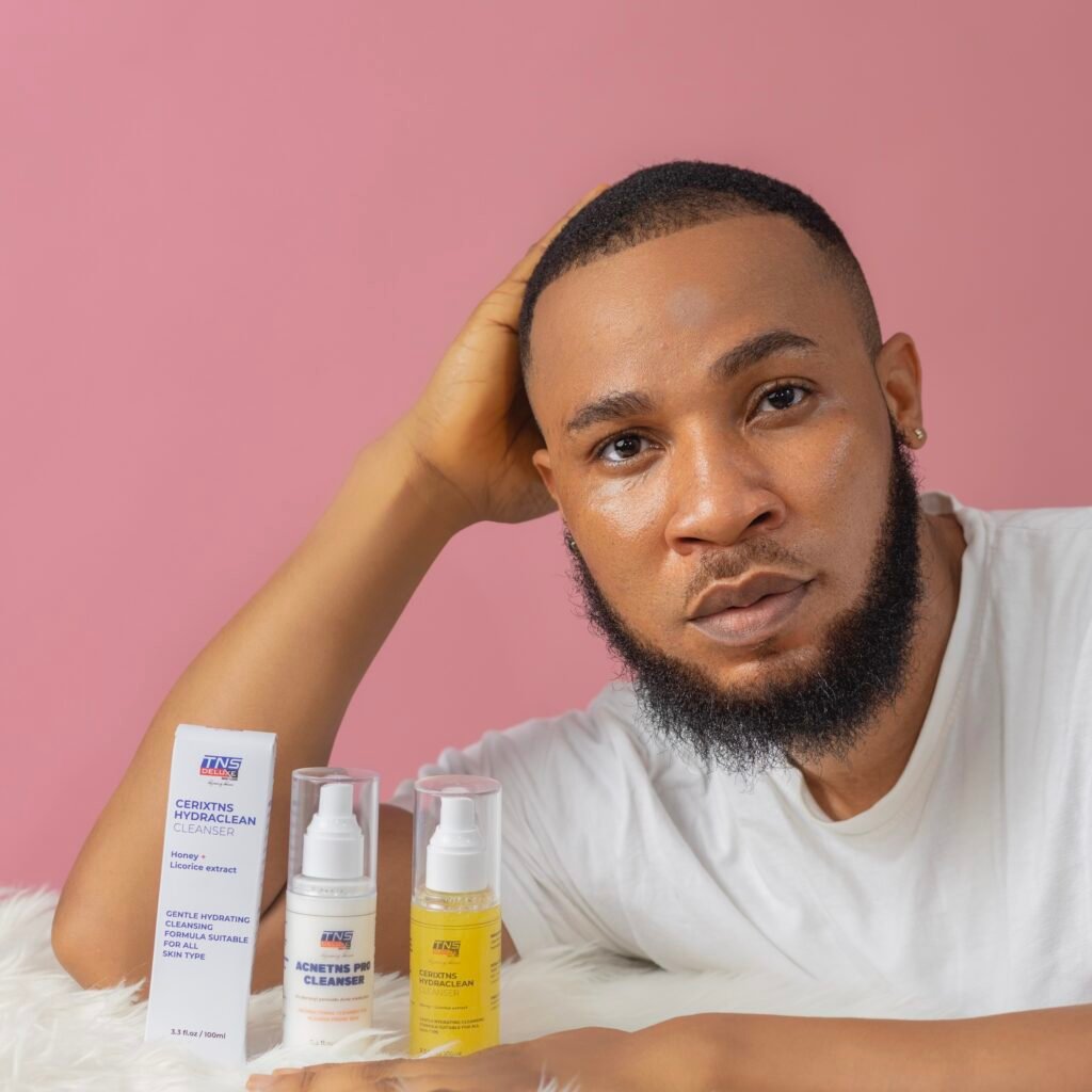 image of a model with clear skin, leaning on a table with TNS skin care products