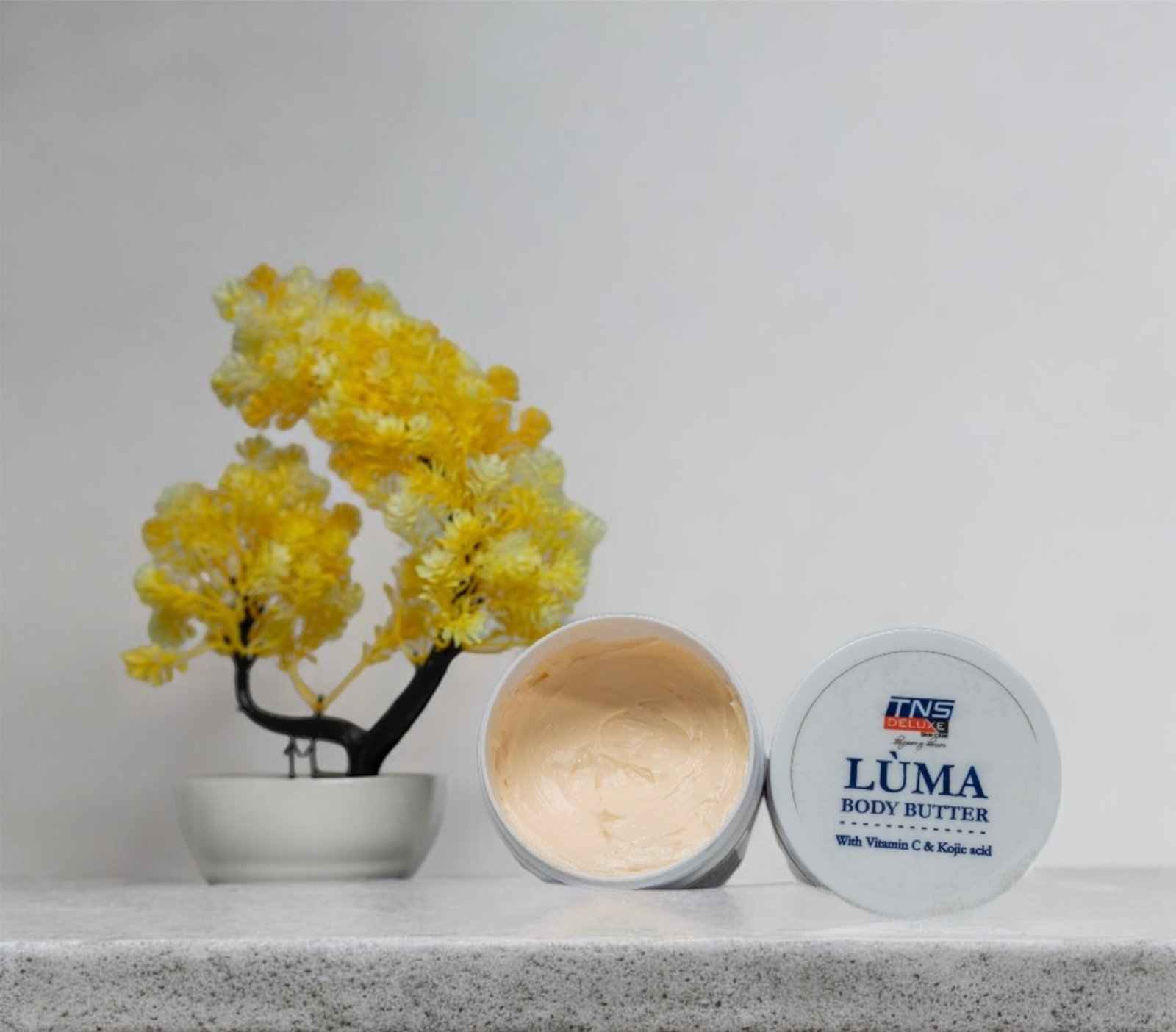 A creative image of teh luma body butter with a flower in the background